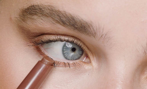 Macro shot of model applying matte Shadowstix Longwear Eyeshadow Stick to waterline.