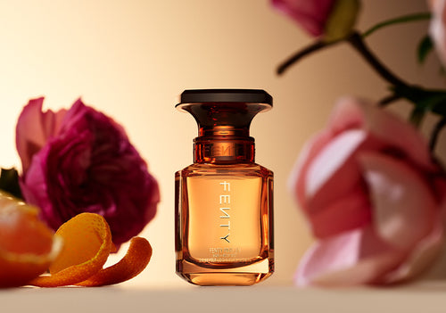 Fenty Parfum Hair + Body Mist against a background with flowers and citrus.