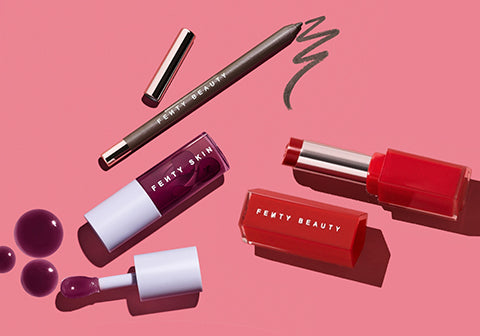 Fenty Skin Fenty Treatz Lip Oil in Black Cherry, Fenty Beauty Trac'd Out Lip Pencil Lip Liner, and Gloss Bomb Stix Gloss Stick on a pink background.